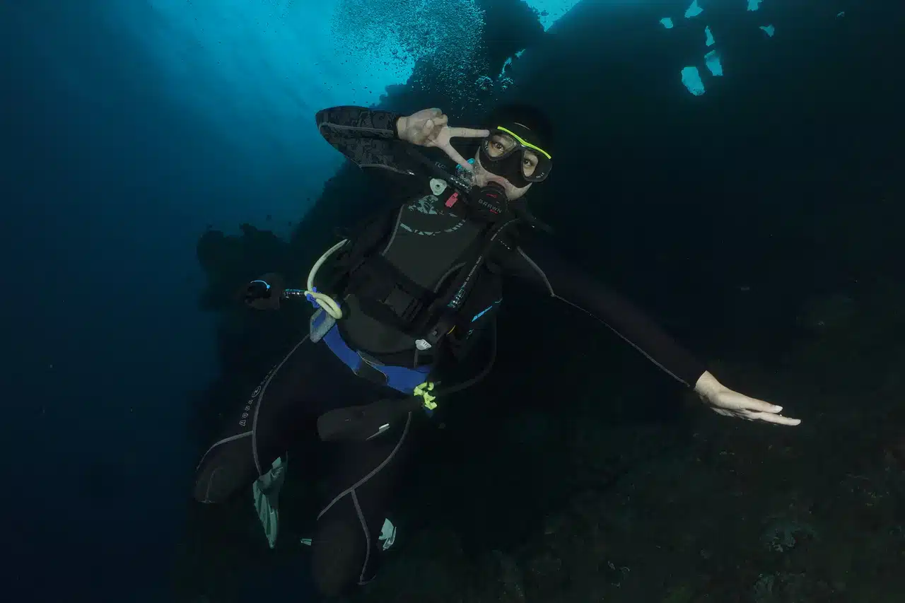 Scuba diver wearing a full wetsuit and diving equipment underwater.
